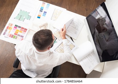 A Man Makes An Estimate Of Construction Work. Calculating The Cost Of A New Home. Construction Engineer At His Desk. Work On A Construction Project.