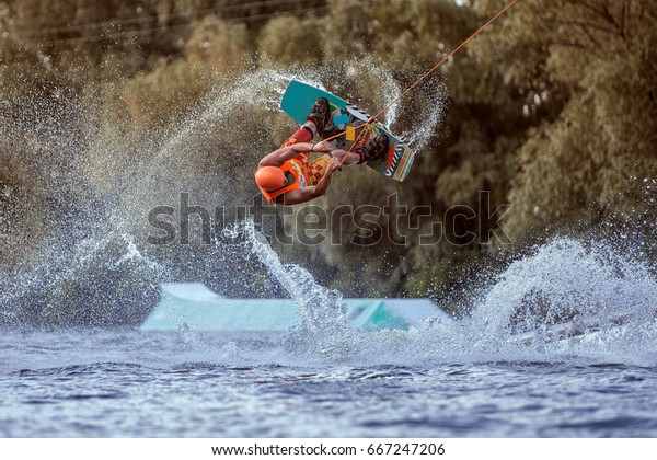 Man makes an extreme jump on wakeboarding, around
there are a lot of splashes and splashes of water. This is an
extreme sport.