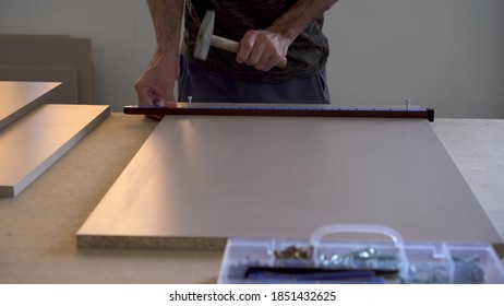 A Man Makes Markings On Wooden Parts In A Furniture Manufacturing Facility.