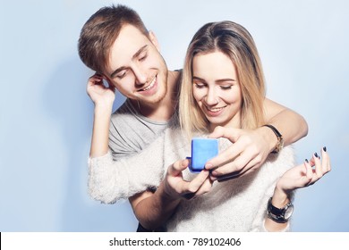 Man Makes Present  To His Lovely Sweetheart Girl. Jewelry In Blue Box.  Young Man Giving A Gift. Lover's Valentine Day. Valentine Couple. Family. Boy Gives To His Girlfriend Jewelry.