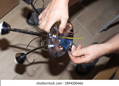 a man makes wiring on a chandelier for hanging from the ceiling in an apartment. Improvement and repair of premises.