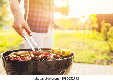 Man making barbecue, assorted vegetables and chicken wings with sausages, grilling on a portable barbecue outdoors in a park in nature