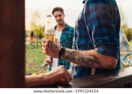 Man making barbecue, assorted vegetables and chicken wings with sausages, grilling on a portable barbecue outdoors in a park in nature