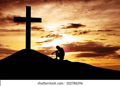 A man making a confession to the cross, shot under dawn sky