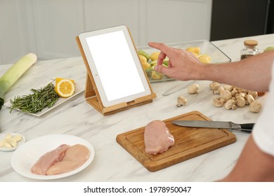 Man Making Dinner While Watching Online Cooking Course Via Tablet In Kitchen, Closeup