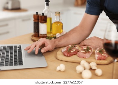 Man making dinner while watching online cooking course via laptop in kitchen, closeup - Powered by Shutterstock