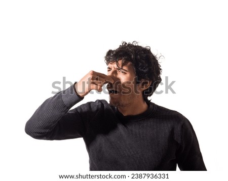 A man making a funny face with his finger, closing his nose because of foul smell or bad odour
