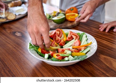 Man Making Healthy Fresh Salad In Kitchen