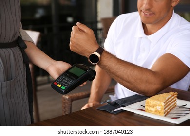 Man Making Payment With Smart Watch In Cafe, Closeup