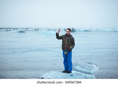 Man Making Photo By Phone Standing On Ice Block