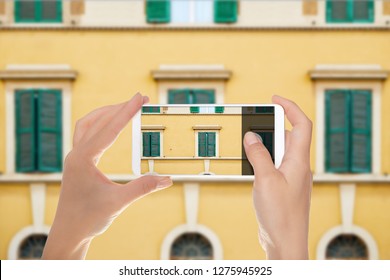 A man is making a photo of pattern from windows of the facade of one of the buildings in Rome, Italy on a mobile phone