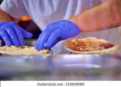 A Man Is Making Pizza With The Blue Gloves