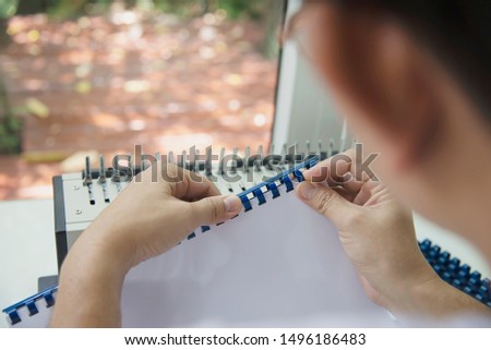 Man making report using comb binding machine - people working with stationary tools concept