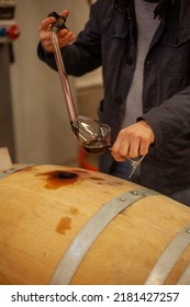 Man Making A Sample Of Red Wine From Barrel With A Special Tool