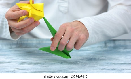 Man Making Yellow Origami Tulip. Origami Flower With Green Stem, Close Up.