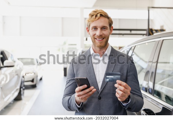 Man male customer client buyer in classic suit\
choose auto want buy new car automobile use credit bank card speak\
by mobile cell phone in showroom salon dealership store motor show\
indoor Sale concept