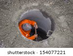 A man in manhole on street, using use a shovel to clean inside a manhole
