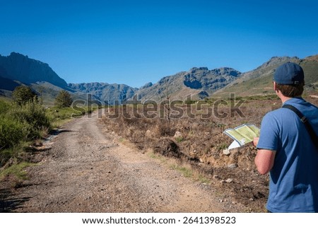 A man with a map stands in the middle of a path in Jonkershoek Nature Reserve. South Africa.