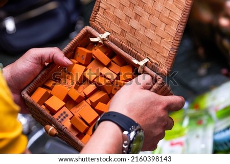 A man in the market holds a box of traditional Chinese mahjong made of bamboo