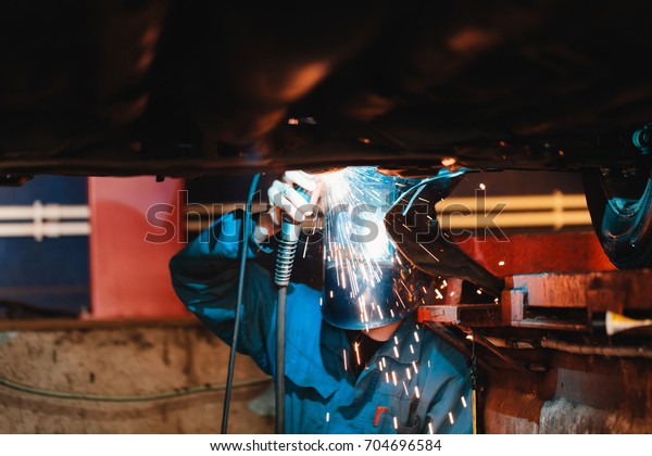 Man in a mask does\
welding machines.