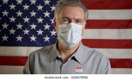 man with a mask during covid in front of an american flag just voted