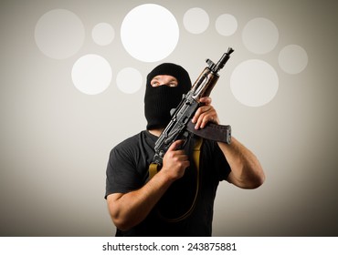 Man in mask with gun having an idea with gray bubbles over his head.