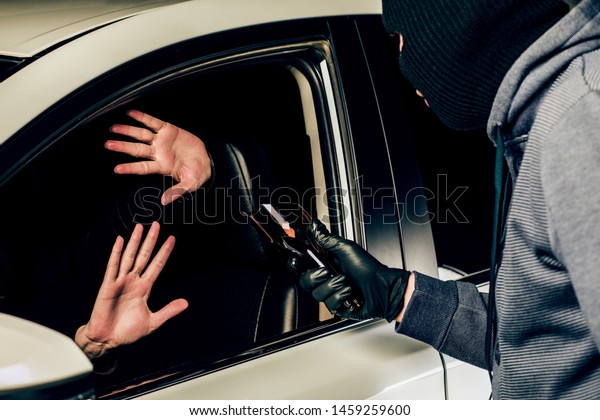 a man in a mask of a\
robber with a broken bottle in his hands threatens a woman in a\
car. robbery.