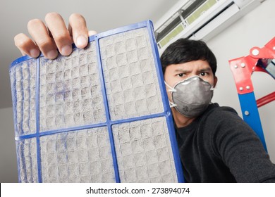 A Man With Mask Showing Dirty Air Filter Before Cleaning