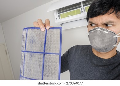 A Man With Mask Showing Dirty Air Filter Before Cleaning