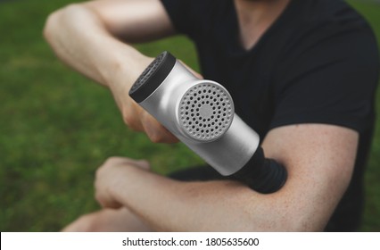 Man massaging his hand with massage percussion device after workout.