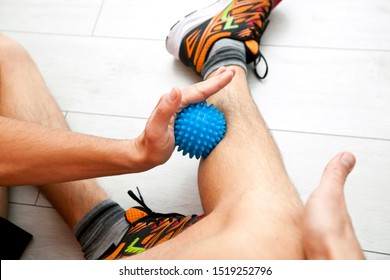 The Man Is Massaging His Leg By Massage Ball At Home