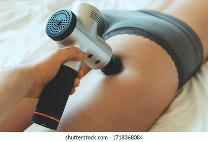 Man Massaging Woman's Leg With Massaging Percussion Device. Percussion Therapy.