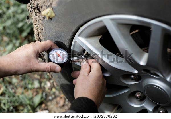 A man measures the air\
pressure with a pressure gauge in the tires of a car. Car traffic\
safety check.