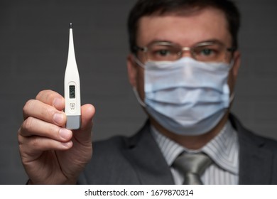 man measures body temperature with a thermometer, has a good his health status, has a protective face mask - healthcare and medicine concept - Powered by Shutterstock