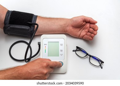 A man measures his own blood pressure on a medical table. Taking care of your own health. Turns on the device - Shutterstock ID 2034039590