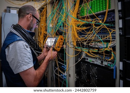 A man measures the optical signal level in a server room. A technician repairs faults in a fiber optic network using a reflectometer.