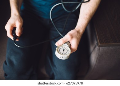 Man measuring blood pressure with tonometer himself at home sitting in armchair