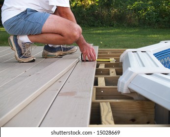 Man Measuring Boards For A New Above Ground Pool Deck