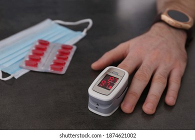 Man measuring oxygen level with modern fingertip pulse oximeter at grey table, closeup - Shutterstock ID 1874621002