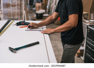 Man measuring a surface with a square in a workshop