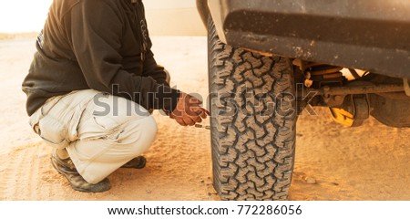 Man measuring tire pressure with meter. Jeep 4x4.