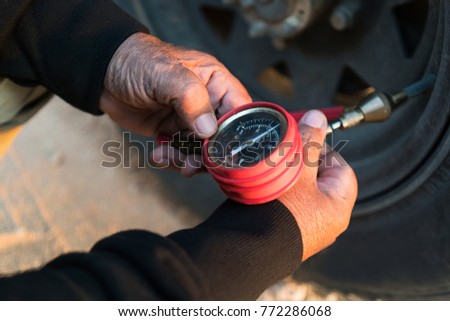 Man measuring tire pressure with meter. Jeep 4x4.