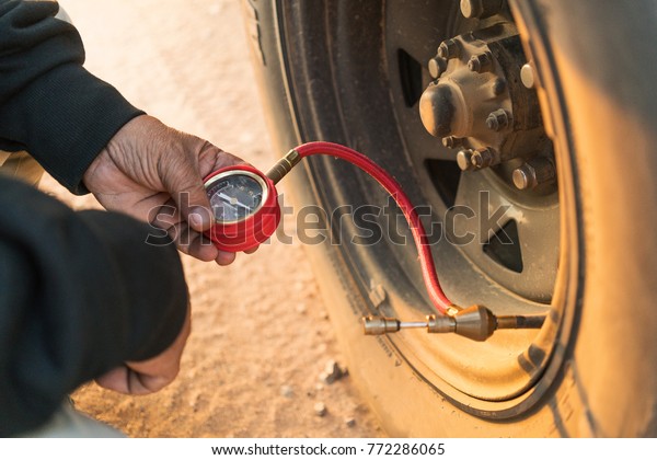 Man measuring tire\
pressure with meter. 