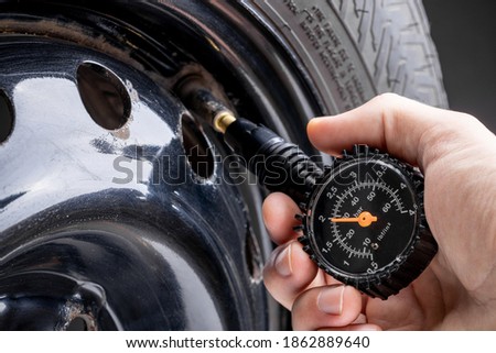 man measuring tyre air pressure by using pressure gauge. car service concept. studio shot.