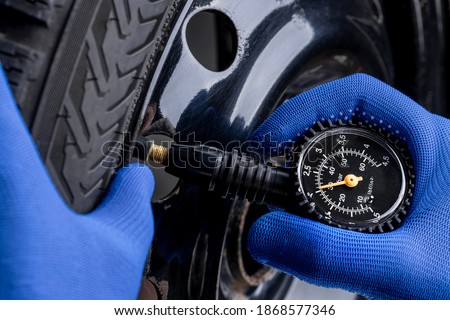 man measuring tyre air pressure by using pressure gauge. car service concept. studio shot.