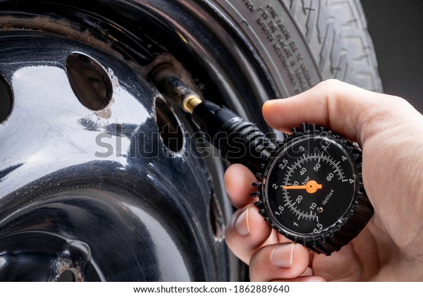 man measuring tyre air pressure by\
using pressure gauge. car service concept. studio\
shot.