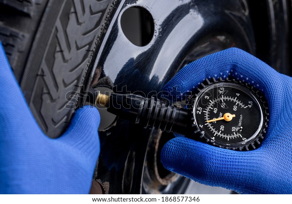 man measuring tyre air pressure by\
using pressure gauge. car service concept. studio\
shot.