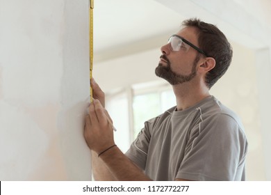 Man measuring a wall using a folding ruler: home renovation and construction concept