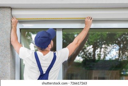 Man Measuring Window Prior To Installation Of Roller Shutter Outdoors