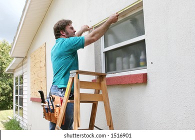 A Man Measuring Windows For Hurricane Shutters Or Plywood.